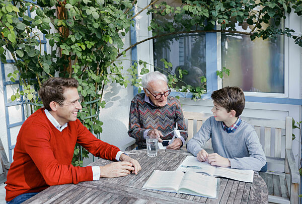 Smiling man looking at son and father talking over turbine model in backyard