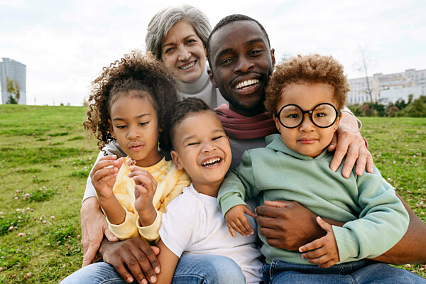 Smiling father sitting with family together on grass
