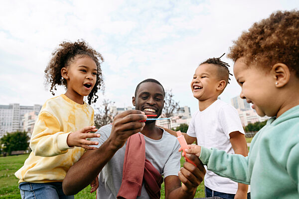 Cheerful children standing with father at park