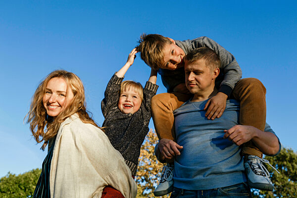 Happy parents carrying playful sons on sunny day
