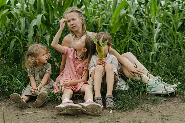 Mother sitting with son and daughters in corn field