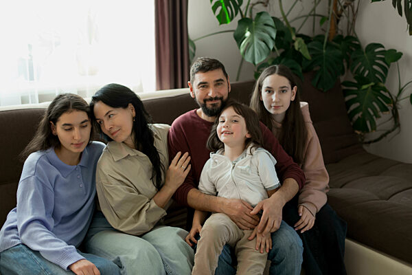 Smiling family sitting together on sofa at home