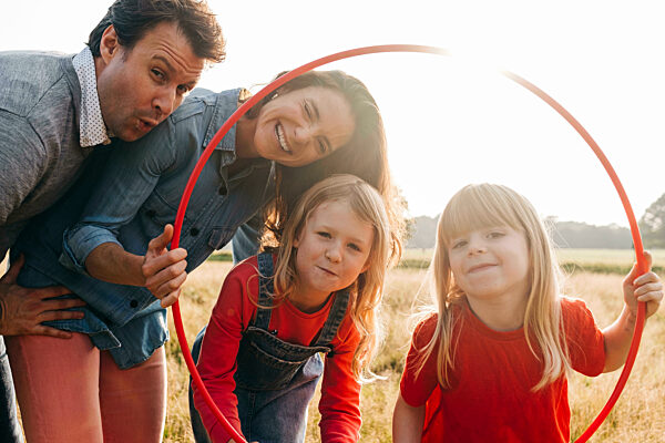 Happy family with hula hoop in park on sunny day