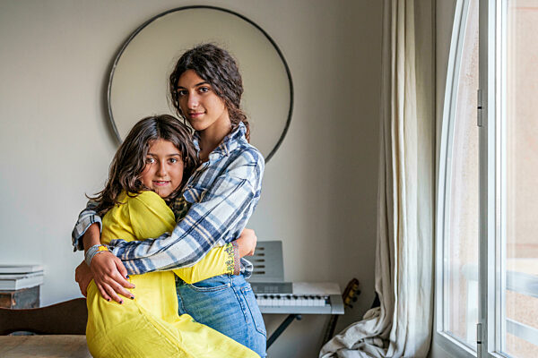 Sisters hugging each other at home