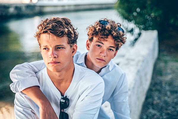Teenage boy arm around young brother