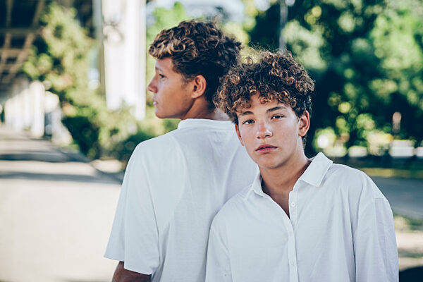 Teenage boy standing back to back with elder brother