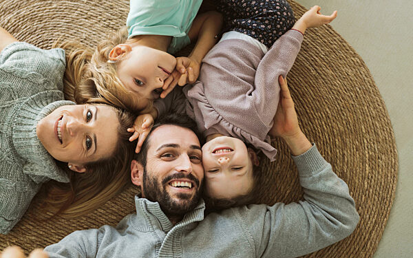 Happy parents with children lying on rug at home