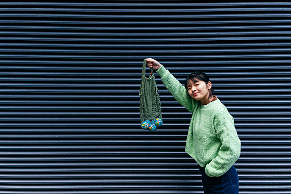Woman holding small globes in mesh bag by corrugated wall