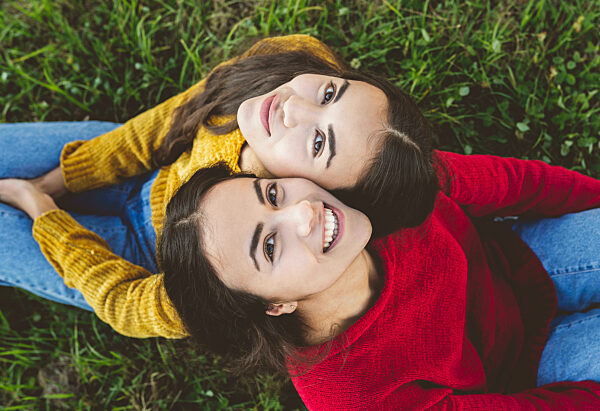Smiling twin sister sitting on grass
