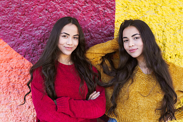 Young sisters smiling in front of colorful wall