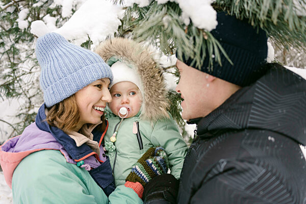 Woman with daughter talking to man under tree in winter
