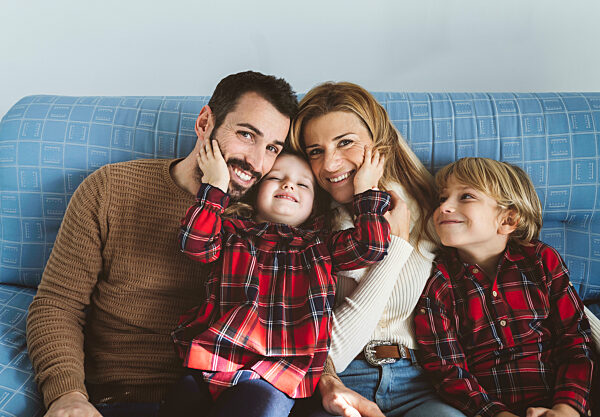 Happy family sitting together on sofa in living room