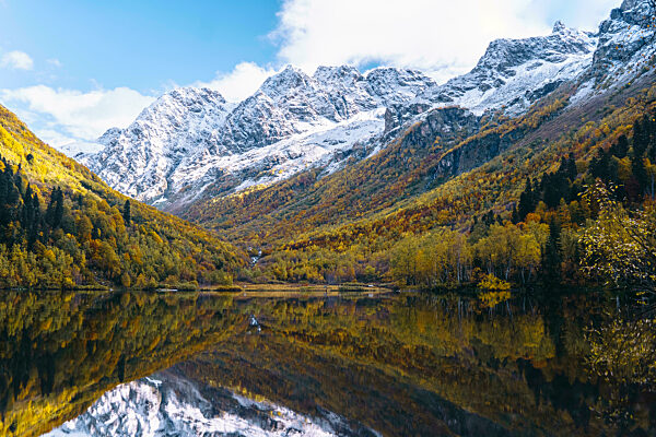 Snow covered mountains reflecting on lake in autumn, Caucasus Nature Reserve, Sochi, Russia