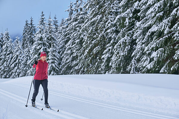 Senior woman skiing in winter forest