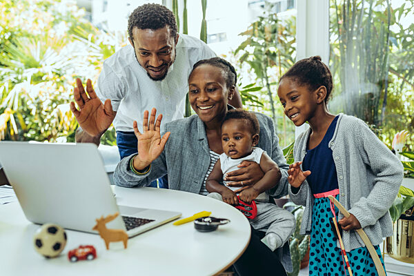 Happy businesswoman with family waving on video call over laptop