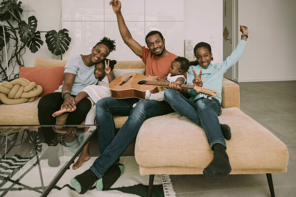 Cheerful family with guitar on couch in living room