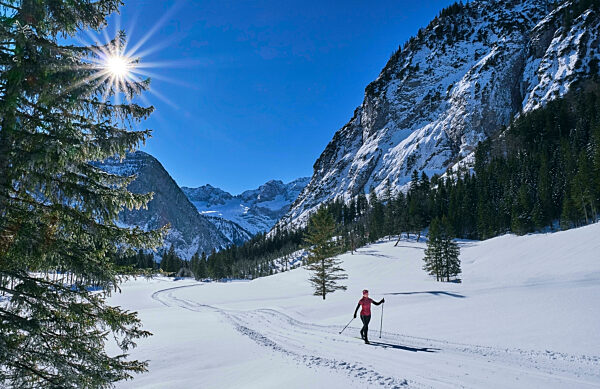 Active senior woman skiing in snow by mountains