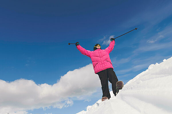 Man with arms raised holding ski poles standing on snow