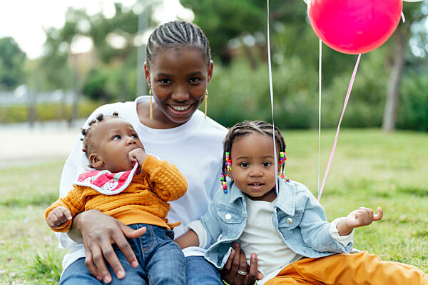 Smiling woman with cute daughter sitting at park