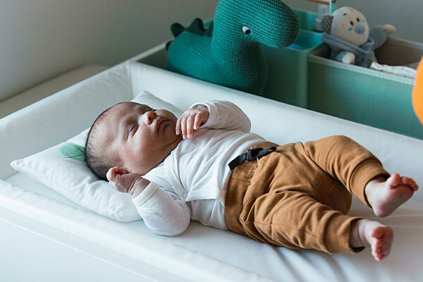 Cute baby boy lying in crib at home