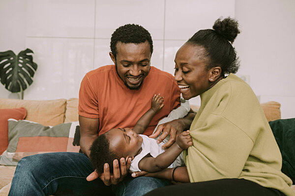 Happy parents tickling baby boy at home