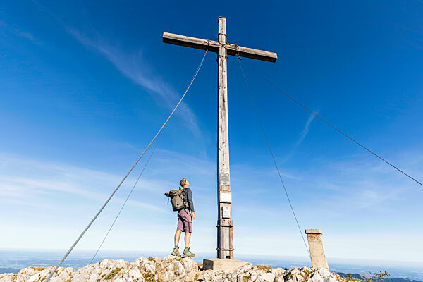 Male hiker standing under summit cross on Benediktenwand