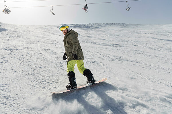 Young man snowboarding on snowcapped mountain