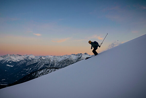 Man skiing on snowcapped mountain at sunset