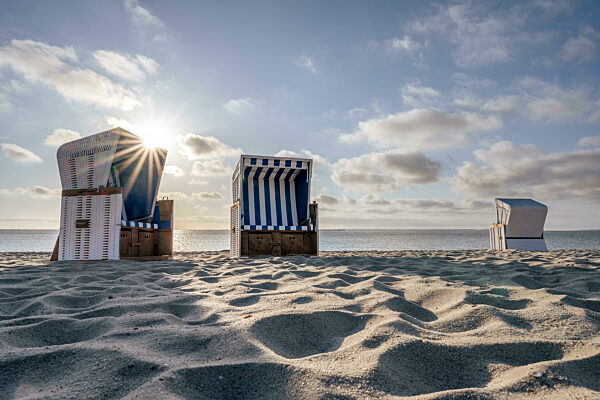 Germany, Schleswig-Holstein, Hornum, Morning sun shining over empty hooded beach chairs standing on sandy beach