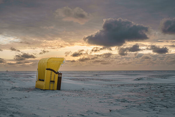 Germany, Lower Saxony, Juist, Hooded beach chair on empty beach at sunset