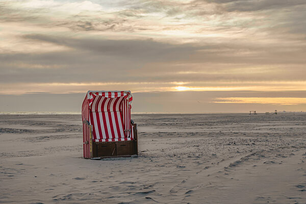 Germany, Lower Saxony, Juist, Hooded beach chair on empty beach at sunset