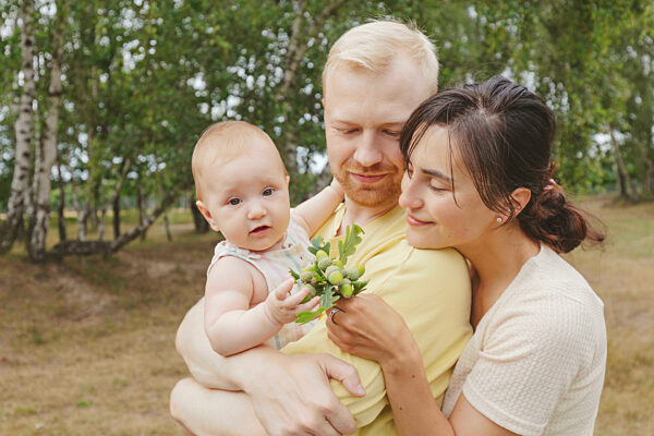 Baby girl in father's arms playing with mother
