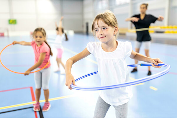 Girl practicing hula hoop at school sports court