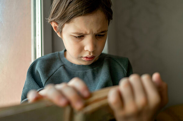 Boy reading book by window at home