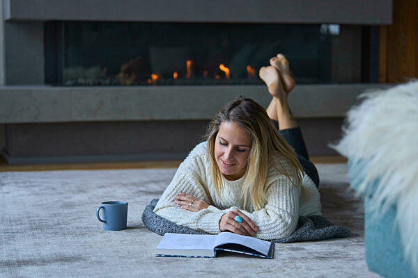 Woman reading book lying at home
