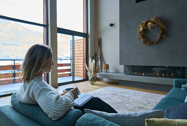 Woman sitting with book and coffee cup sitting on chair at home