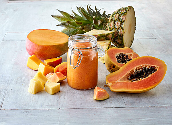 Halved mango fruit, papaya, pineapple and smoothie in jar