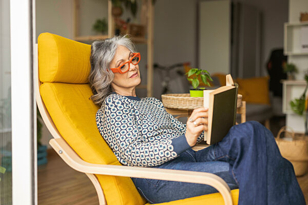 Mature woman reading book sitting on armchair