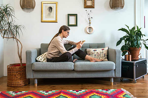 Woman sitting on sofa and reading book