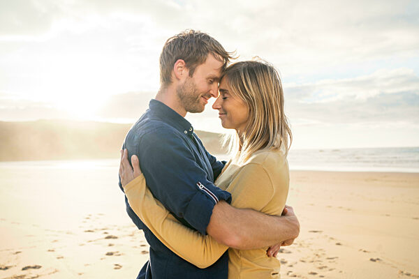 Smiling man and woman embracing each other at beach