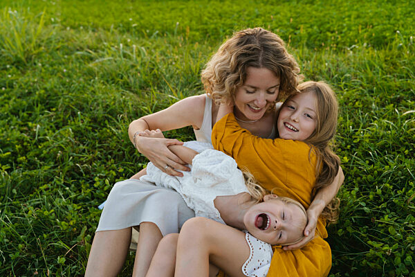 Happy mother enjoying with daughters on grass