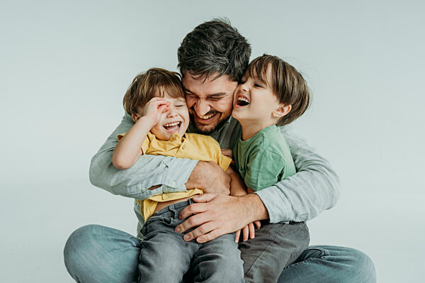 Happy father having fun and hugging children against white background
