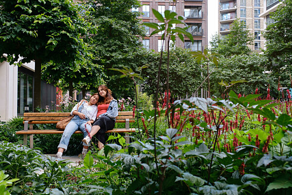 Young gay couple sitting together on bench at park