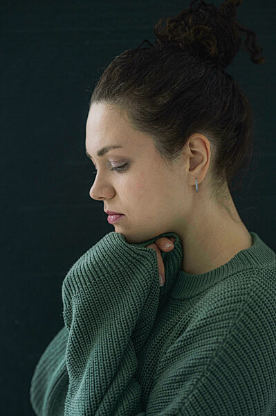 Sad woman wearing green sweater against black background