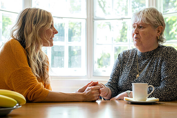 Caregiver listening to depressed senior woman at home