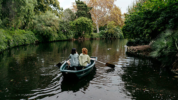 Lesbian couple rowing boat amidst trees in lake at Ciutadella Park, Barcelona, Spain