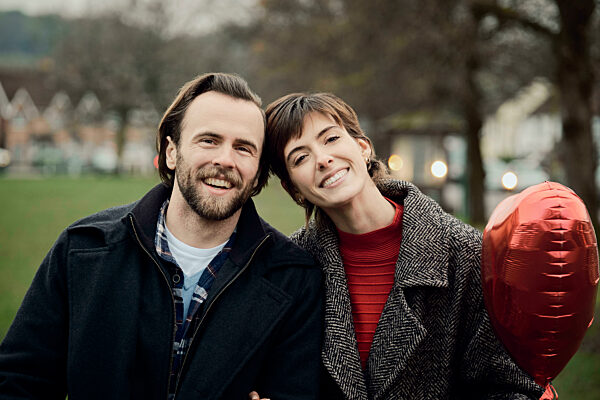 Couple laughing with heart-shaped balloon in a London park