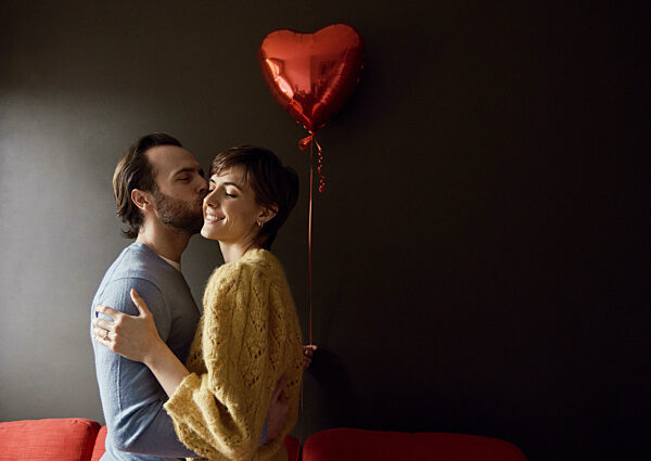 Couple embracing with a heart-shaped balloon in a dark room