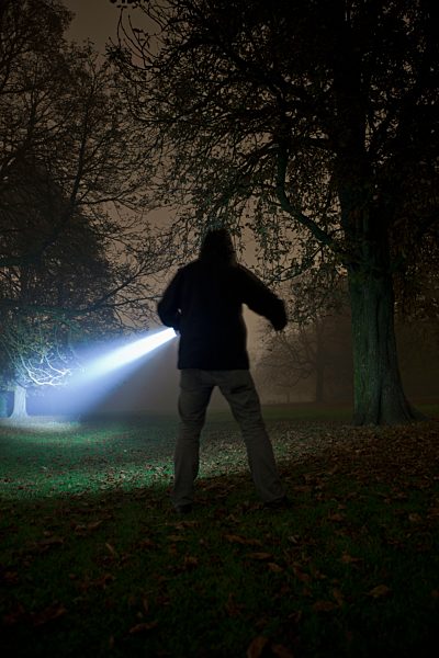 Germany, Munich, Young man with torch in foggy night