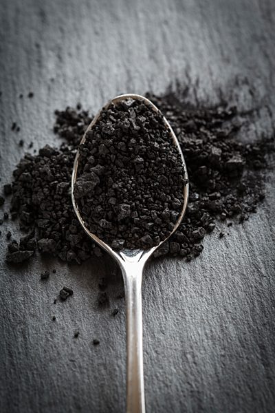 Spoon filled with black salt, close Up